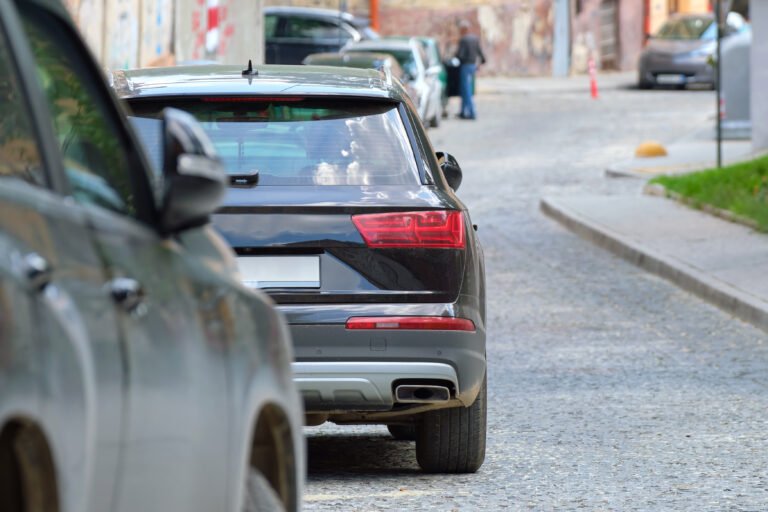 city traffic with cars parked in line on street side.