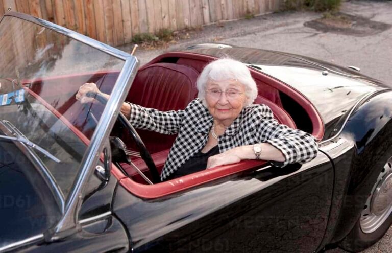 smiling older woman driving convertible